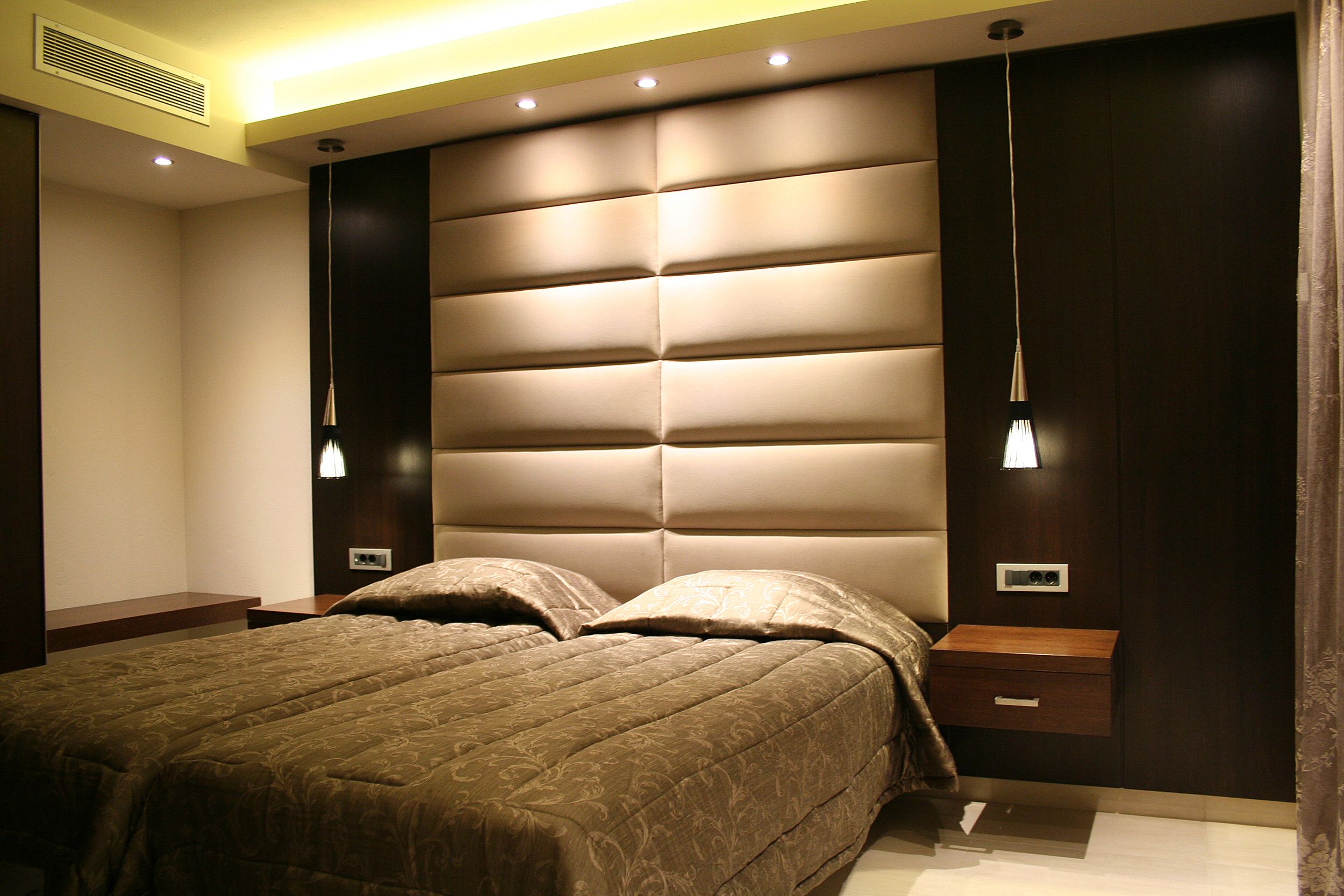 
Elegant bedroom with padded headboard, twin beds and warm pendant lighting at Mike apartments