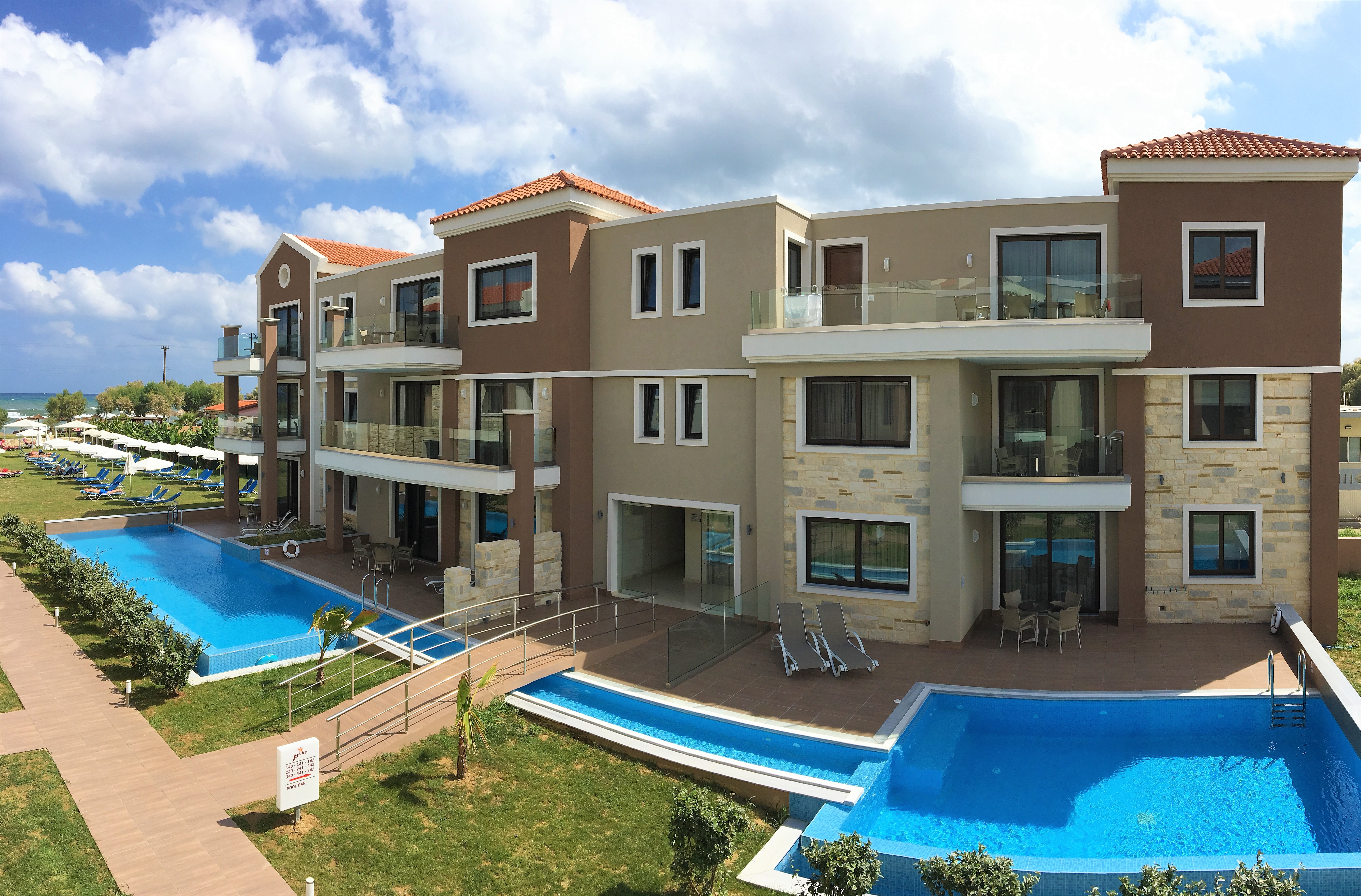 
Panoramic view of the hotel buildings with the pool and white bridge, plus a garden path leading directly to the sea