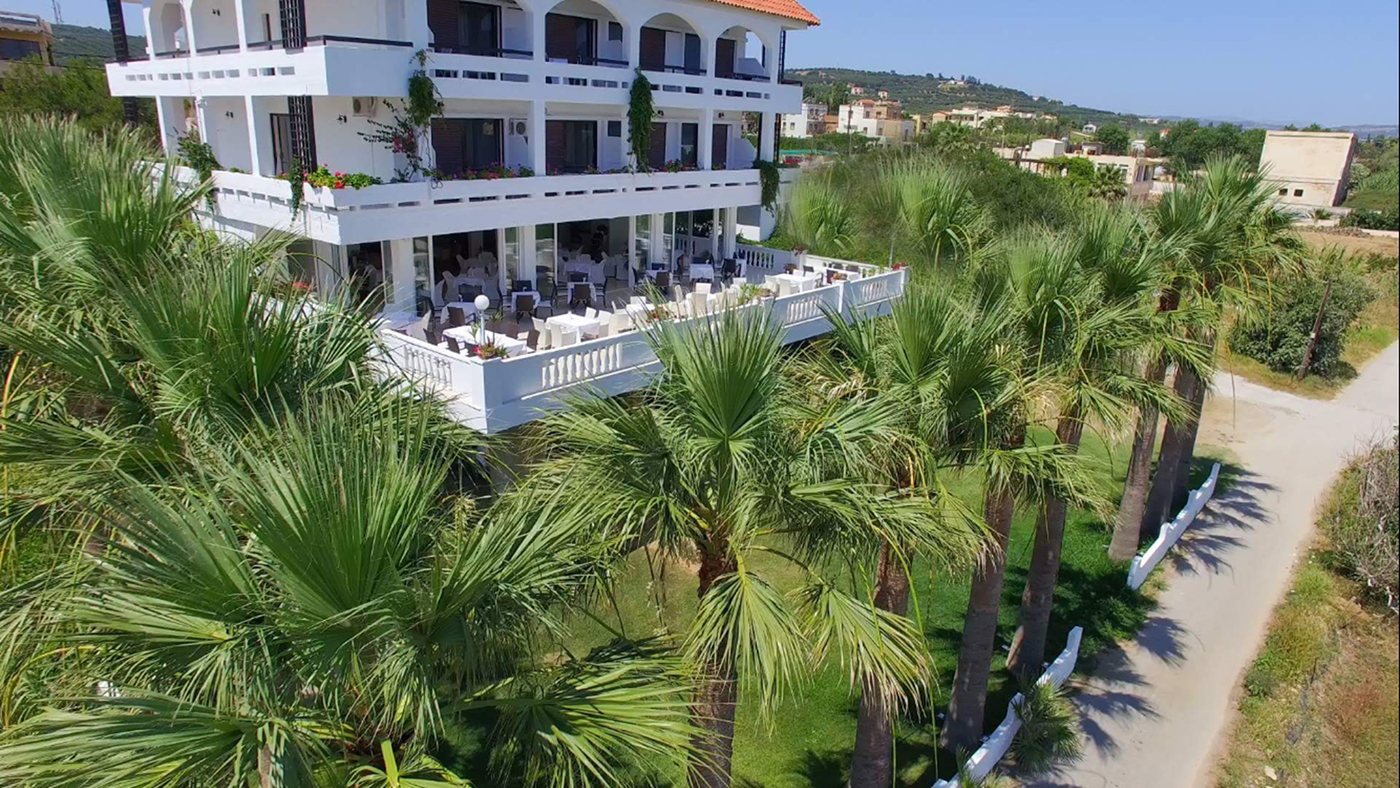 
Aerial view of Mike Hotel surrounded by palm trees and outdoor dining terrace