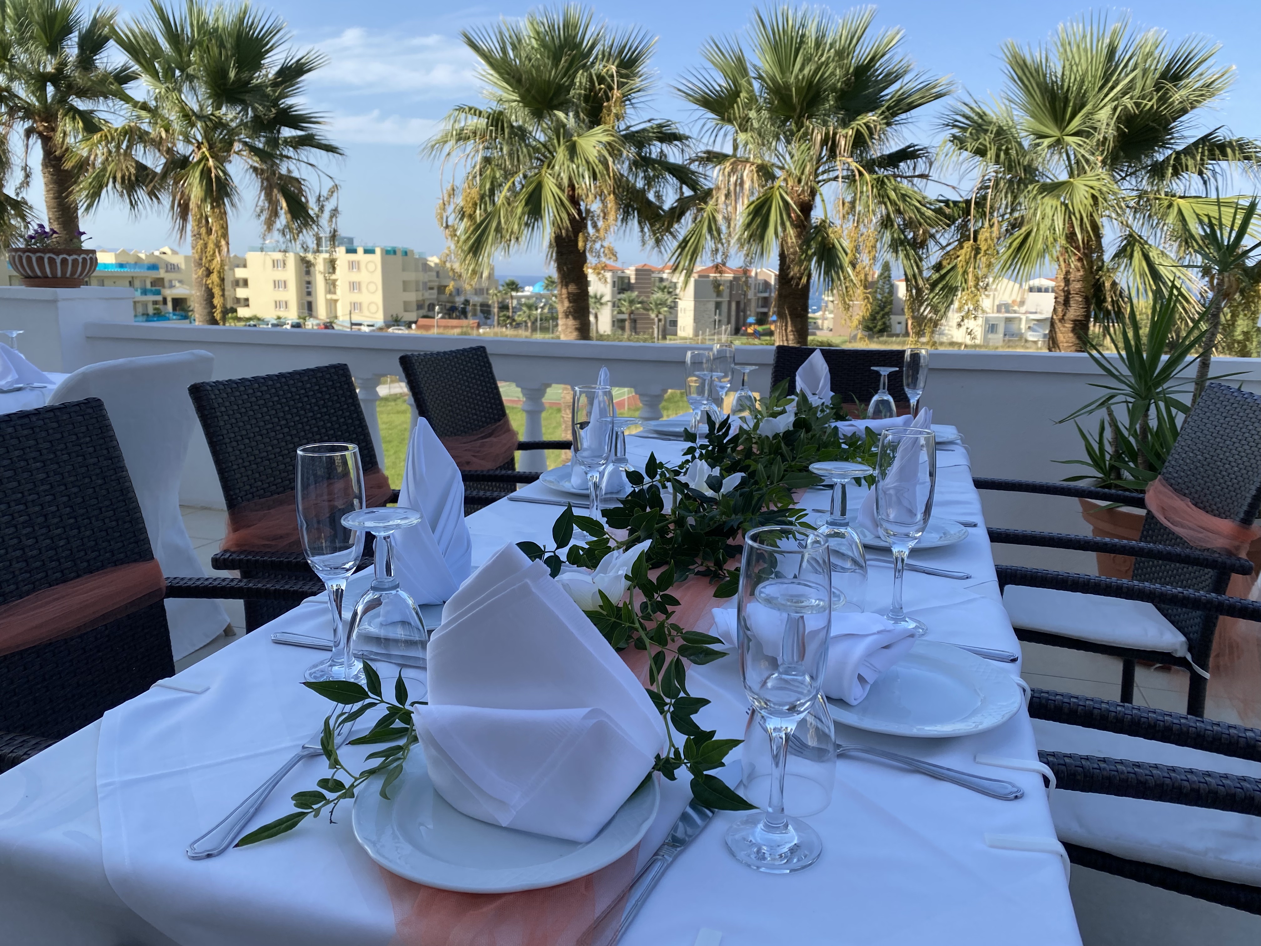 
Restaurant table with white tablecloth, coral-orange details and olive branch decor